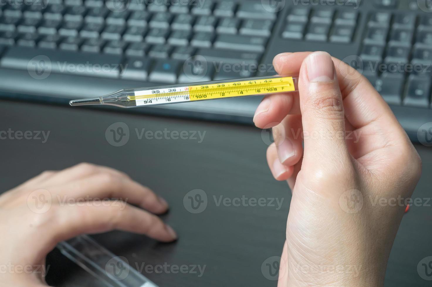woman hand holding clinical thermometer on working desk,After using the clinical thermometer and worry about coronavirus spread photo