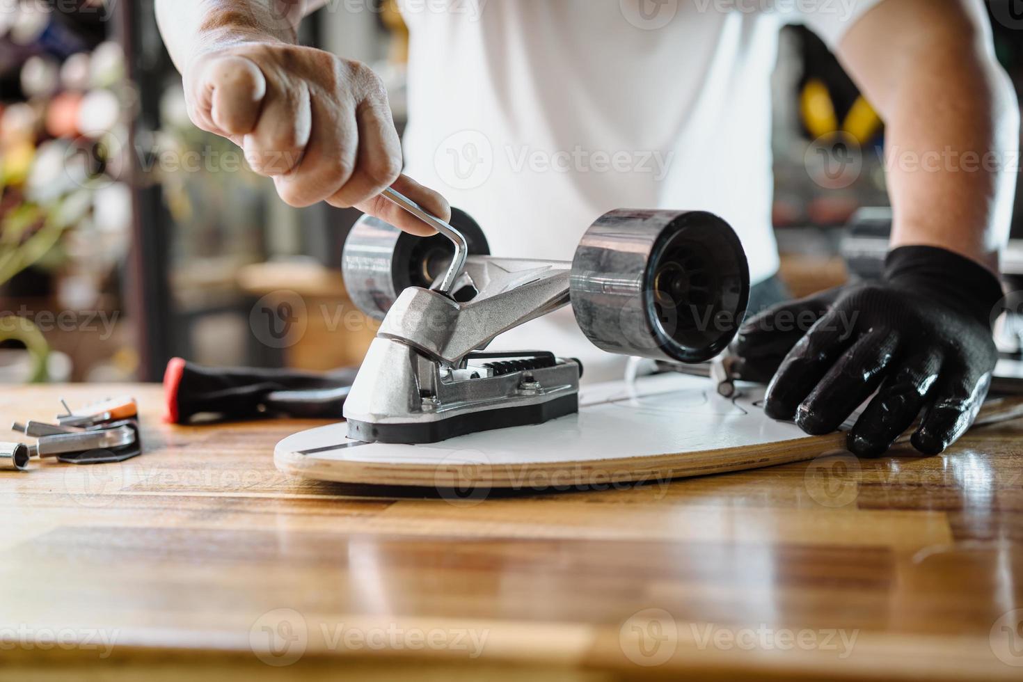 el hombre utiliza la herramienta de enchufe o las llaves hexagonales para quitar las tuercas de la patineta y ajusta la suspensión en el taller, el mantenimiento de la patineta y el concepto de reparación. enfoque selectivo foto