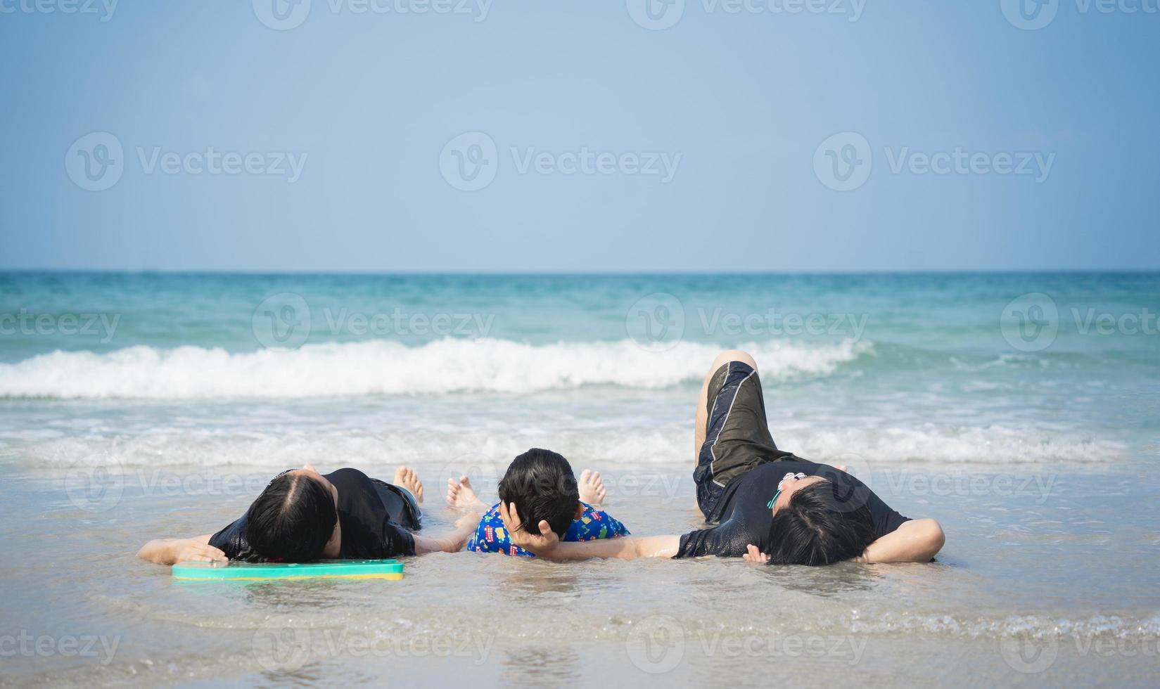 The family asian lying on the beach looking at the blue sea, the island, the sunlight and the blue sky in the morning. photo