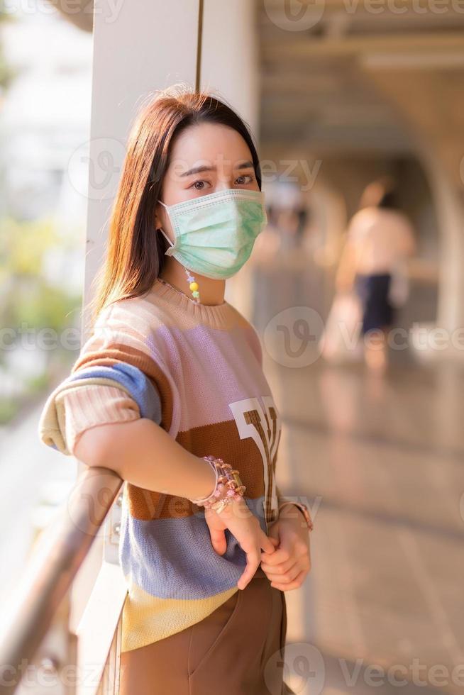 mujer asiática con suéter colorido usa mascarilla médica en un nuevo concepto normal y de atención médica. foto