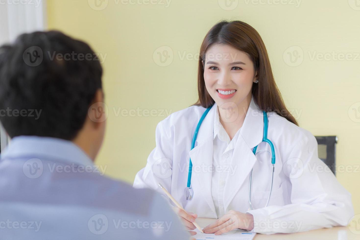 A beautiful Asian female doctor smiled and asked about the symptoms. Stay at the hospital wearing a white robe and stethoscope photo