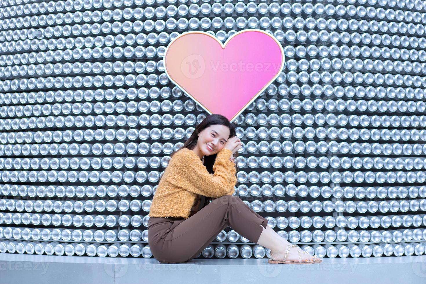 hermosa mujer asiática de pelo largo negro viste abrigo amarillo y sonrisas frescas en el tema de san valentín. foto