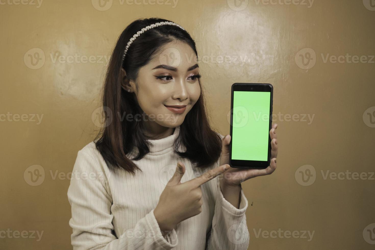 mujeres asiáticas jóvenes felices y sonrientes que muestran una pantalla en blanco verde. foto