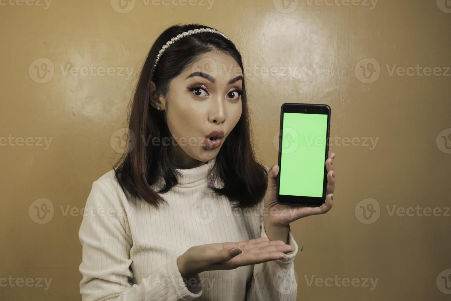 Asian beautiful girl is shocked show green screen in smartphone with white shirt photo