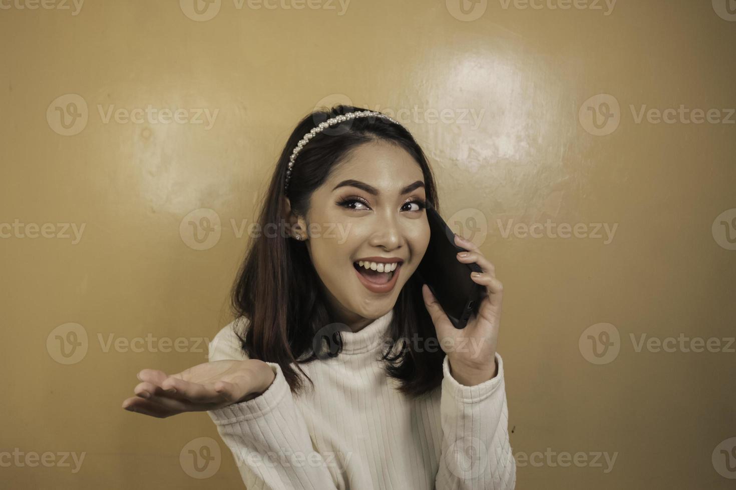 mujer asiática joven sonriente con la mano del gesto de la charla o de la llamada foto