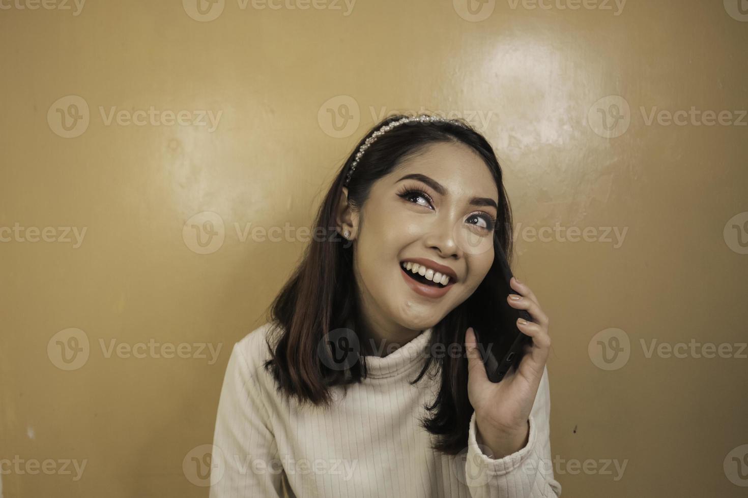 mujer asiática joven sonriente con la mano del gesto de la charla o de la llamada foto