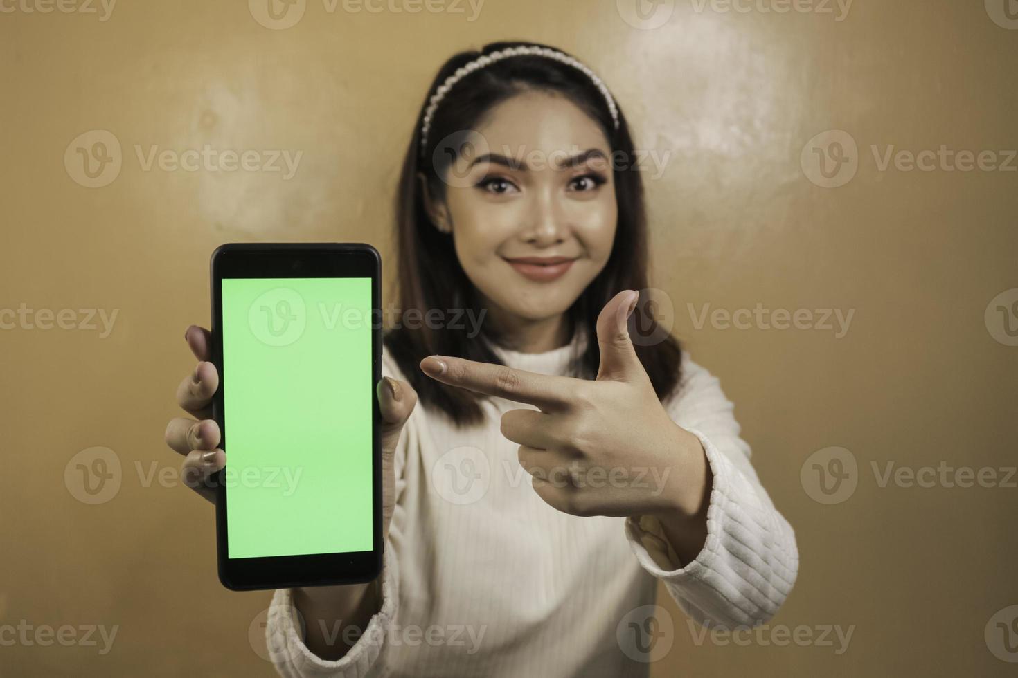 mujeres asiáticas jóvenes felices y sonrientes que muestran una pantalla en blanco verde. foto