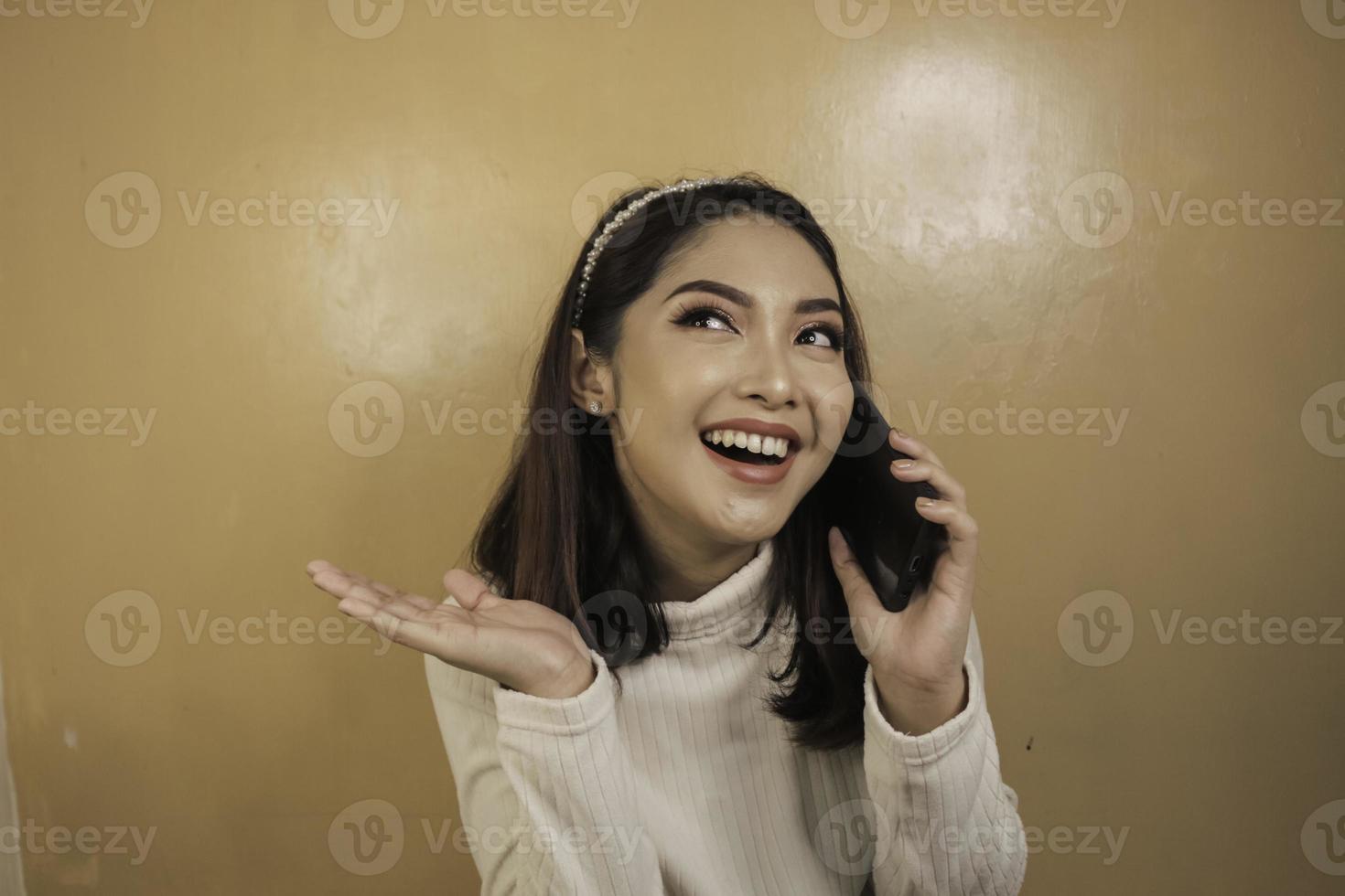 Smiling young asian woman with talk or call gesture hand photo