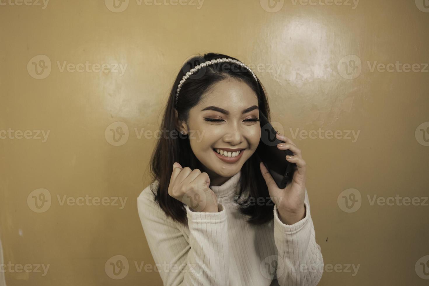 Smiling young asian woman with talk or call gesture hand photo