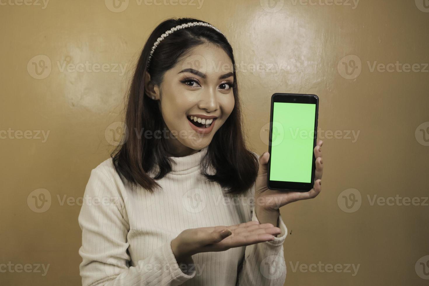 Happy and smiling young Asian women showing a green blank screen. photo