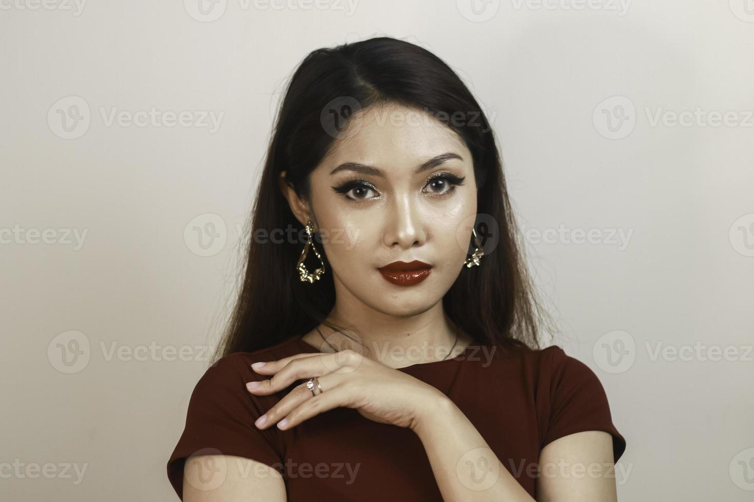 una mujer asiática de aspecto feroz con una camisa roja posando frente a un fondo blanco foto