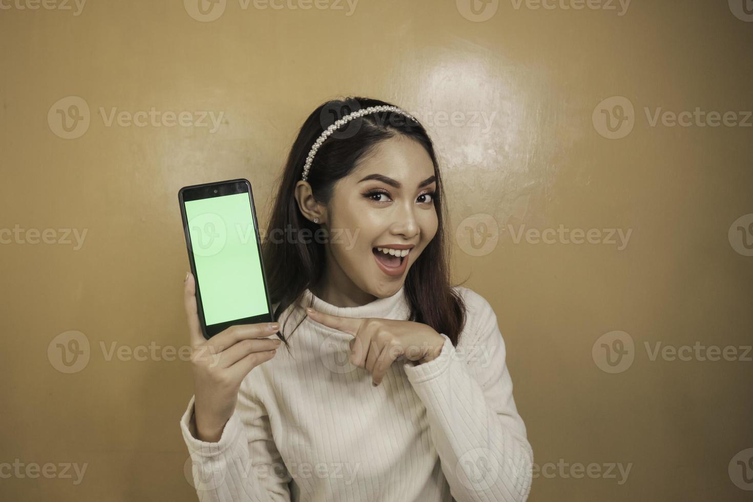 Happy and smiling young Asian women showing a green blank screen. photo