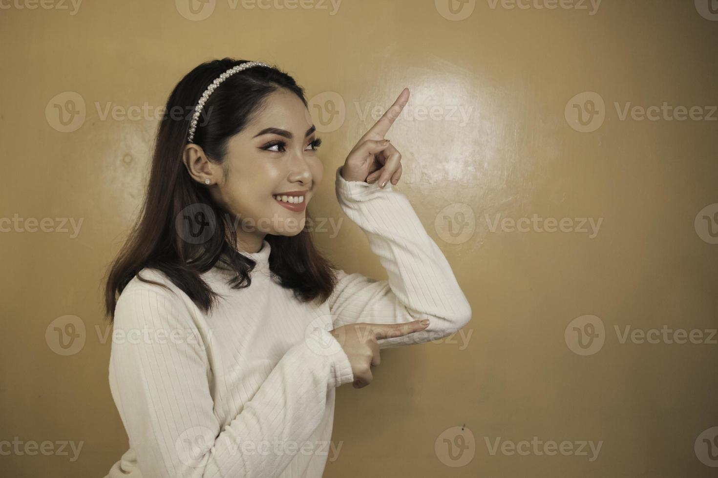 Happy and smile face with smile of young Asian girl with hand point on empty space. photo