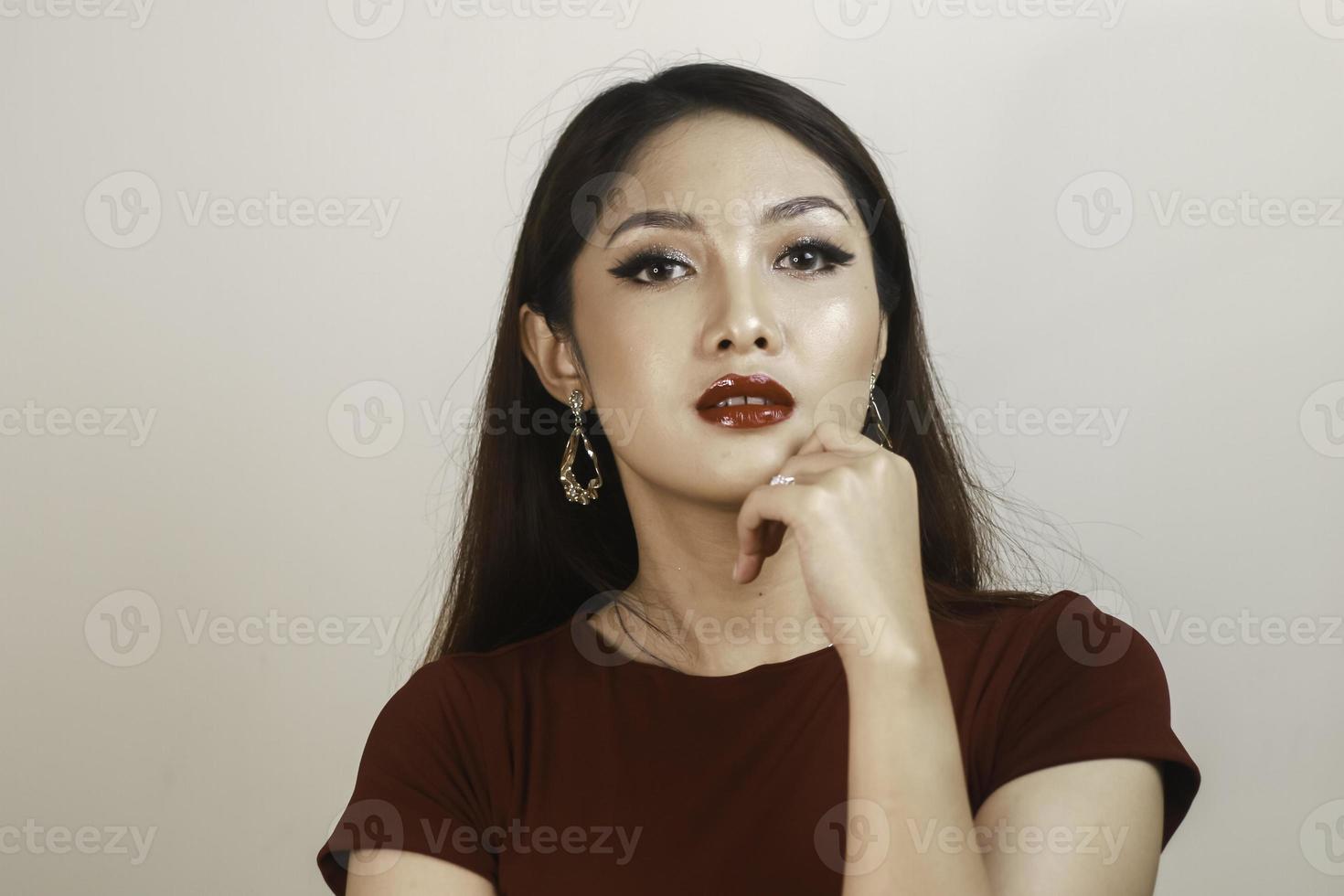 A fierce-looking Asian woman in a red shirt posing in front of white background photo