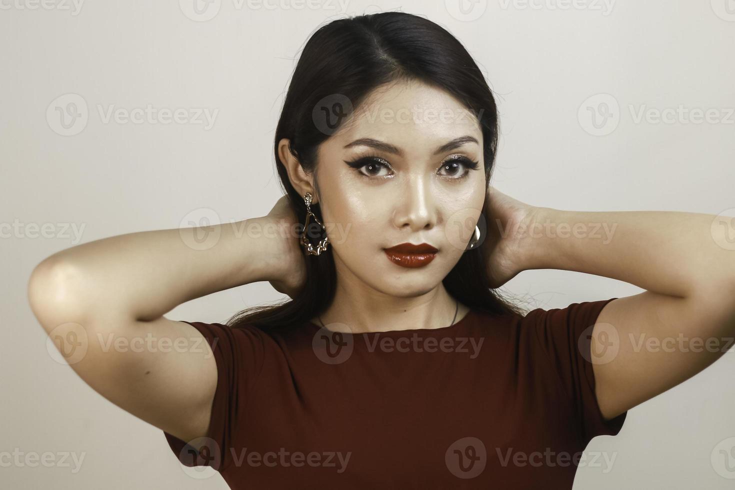 A fierce-looking Asian woman in a red shirt posing in front of white background photo