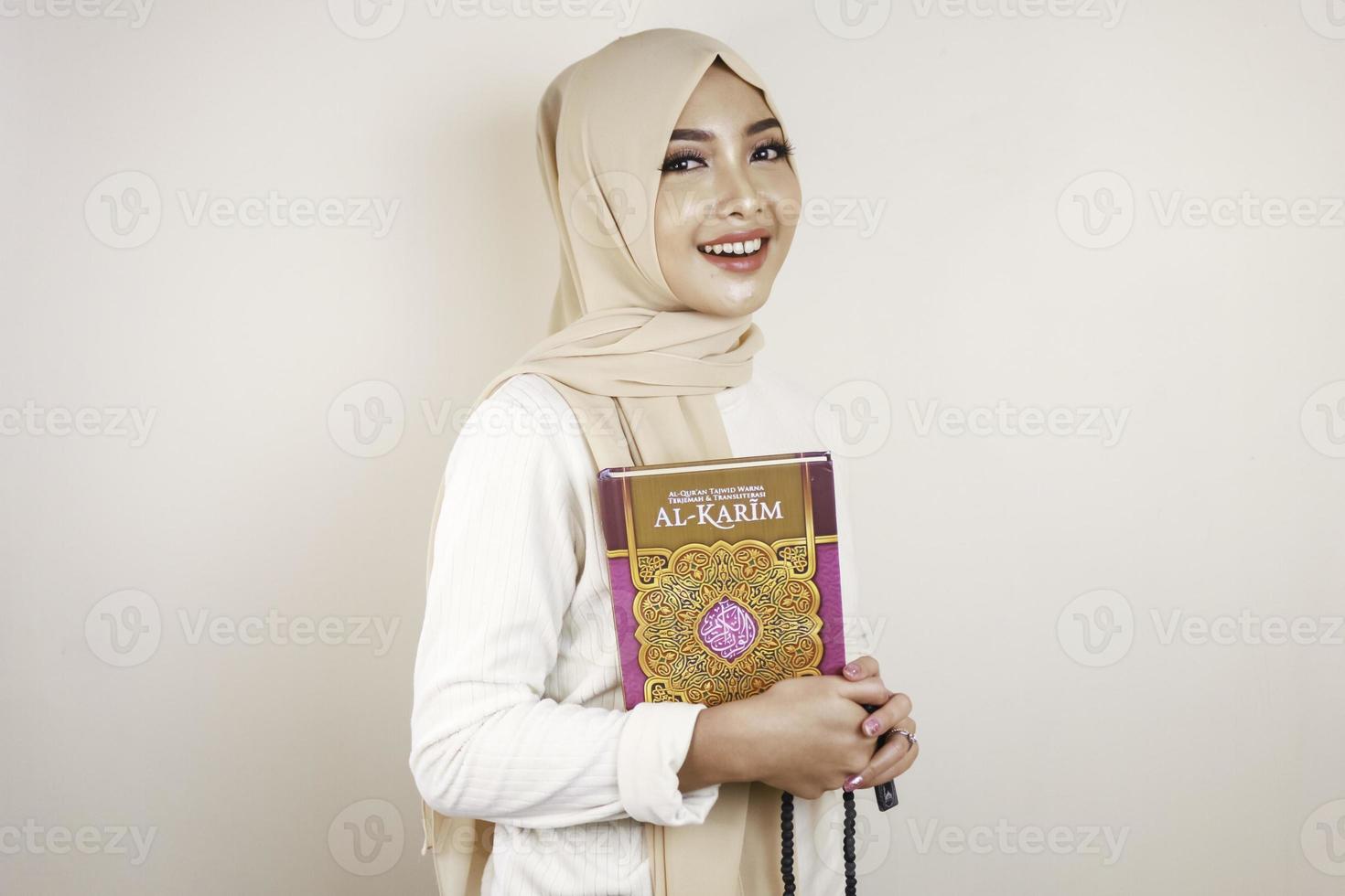 Young Asian Muslim woman smiling and holding the Quran photo