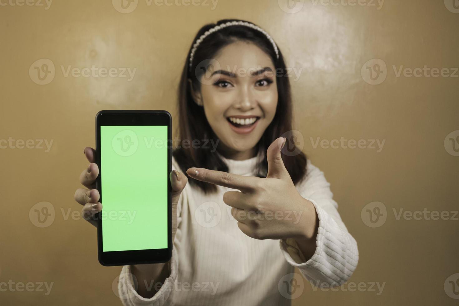 Happy and smiling young Asian women showing a green blank screen. photo