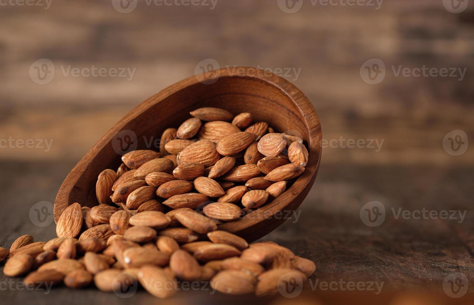 Almonds in wood bowl on wood table.Diet raw material photo