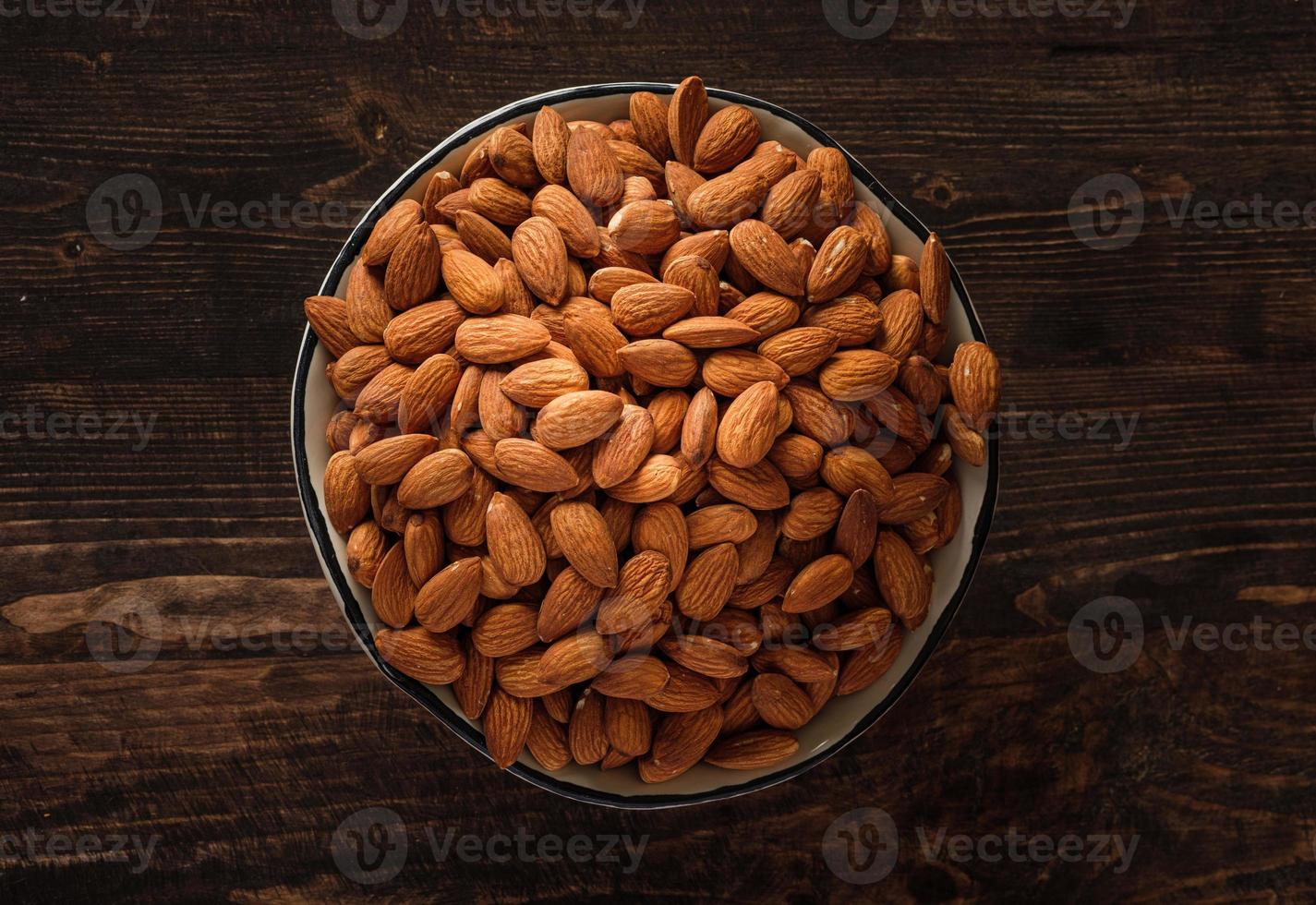 almendras en cuenco de madera sobre mesa de madera.materia prima dietética foto