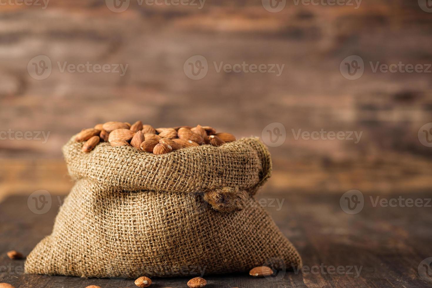 almendras en bolsa de saco sobre mesa de madera.materia prima orgánica foto