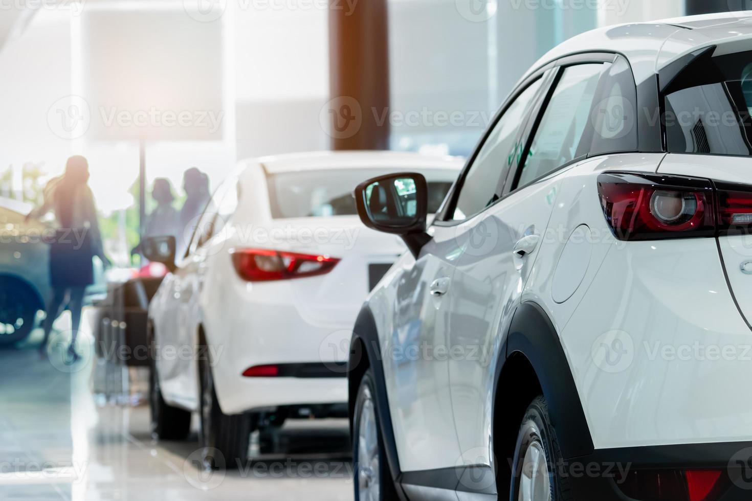 Rearview white SUV car in modern luxury showroom on blur saleswoman and customer. Car dealership office concept. Dealer agent business. Automobile leasing service. Dealer company. New car purchase. photo