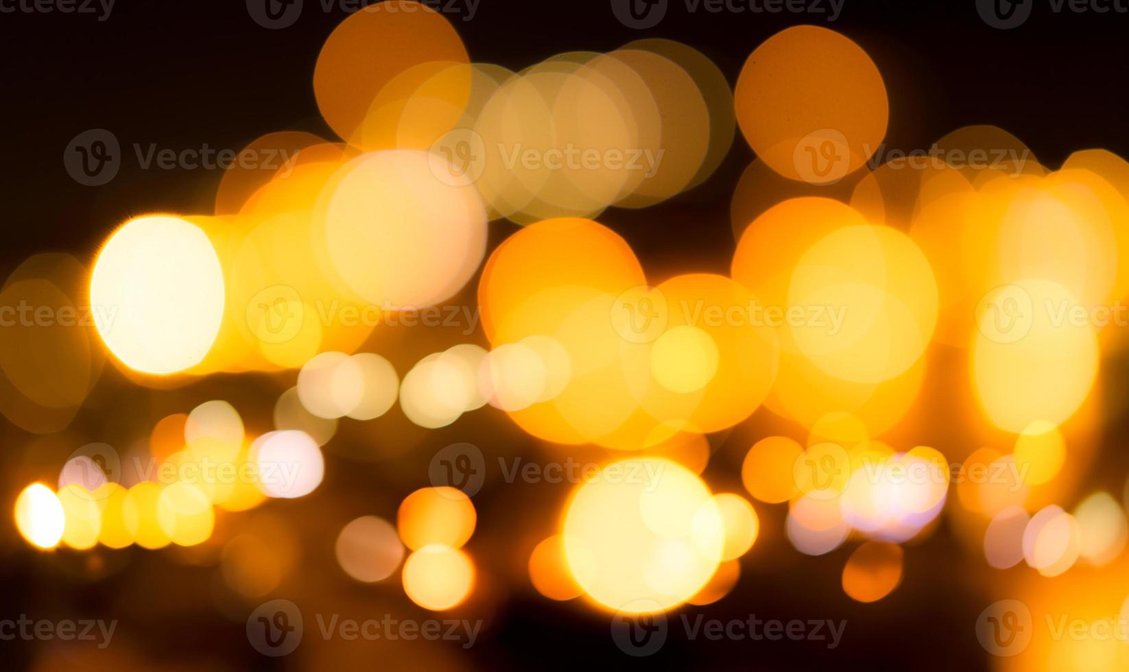 Blurred yellow bokeh background. Blur abstract background of urban light. Warm light with beautiful pattern of round bokeh. Orange light in the night. Street lamp blurred lights in the city at night. photo