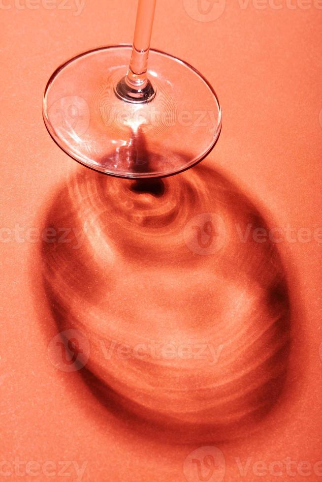 Minimalist still life, wine glass on red background with creative shadow. photo