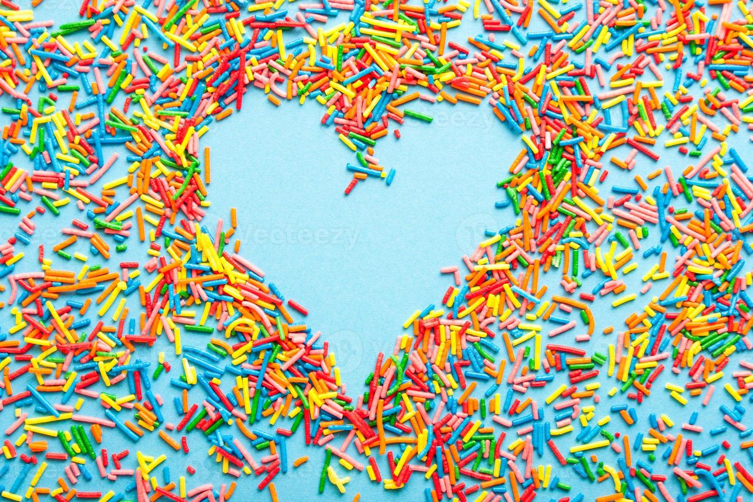 Simple concept flatlay with a heart made of colorful sugar sprinkles. photo