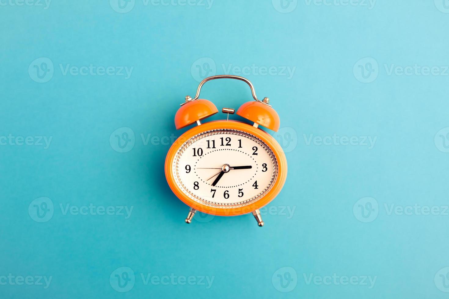 Vintage style orange alarm clock with bells on blue background with free copy paste space for text. photo