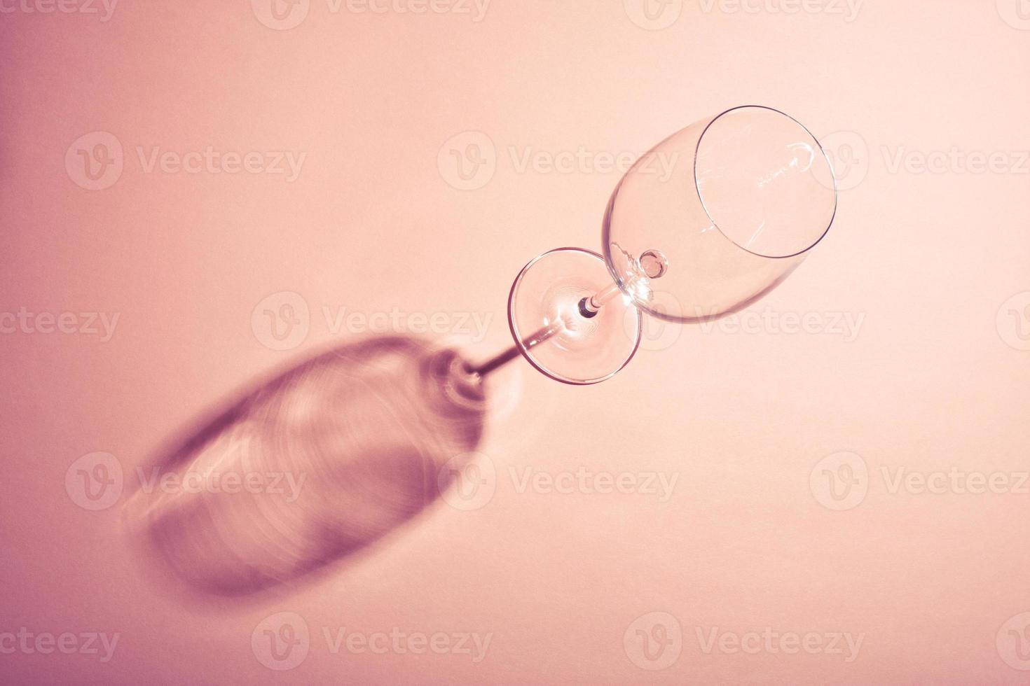 Empty wine glass with creative dark shadow on pink background. photo