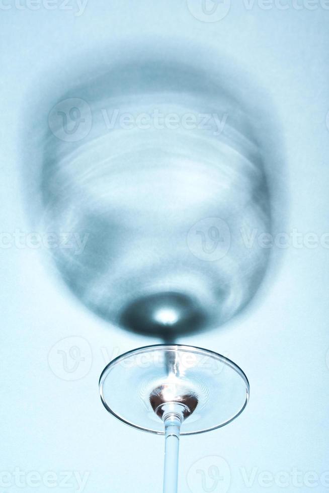 Abstract wine glass shadow on blue background. Minimalist still life image of a wine glass. photo