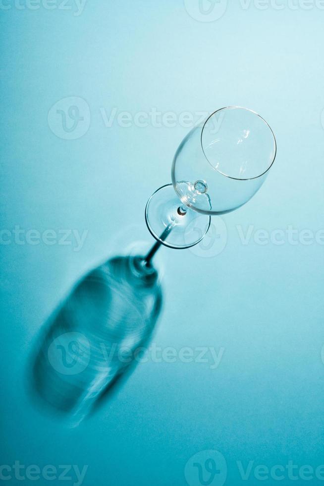 Empty wine glass with a creative shadow on blue background. photo