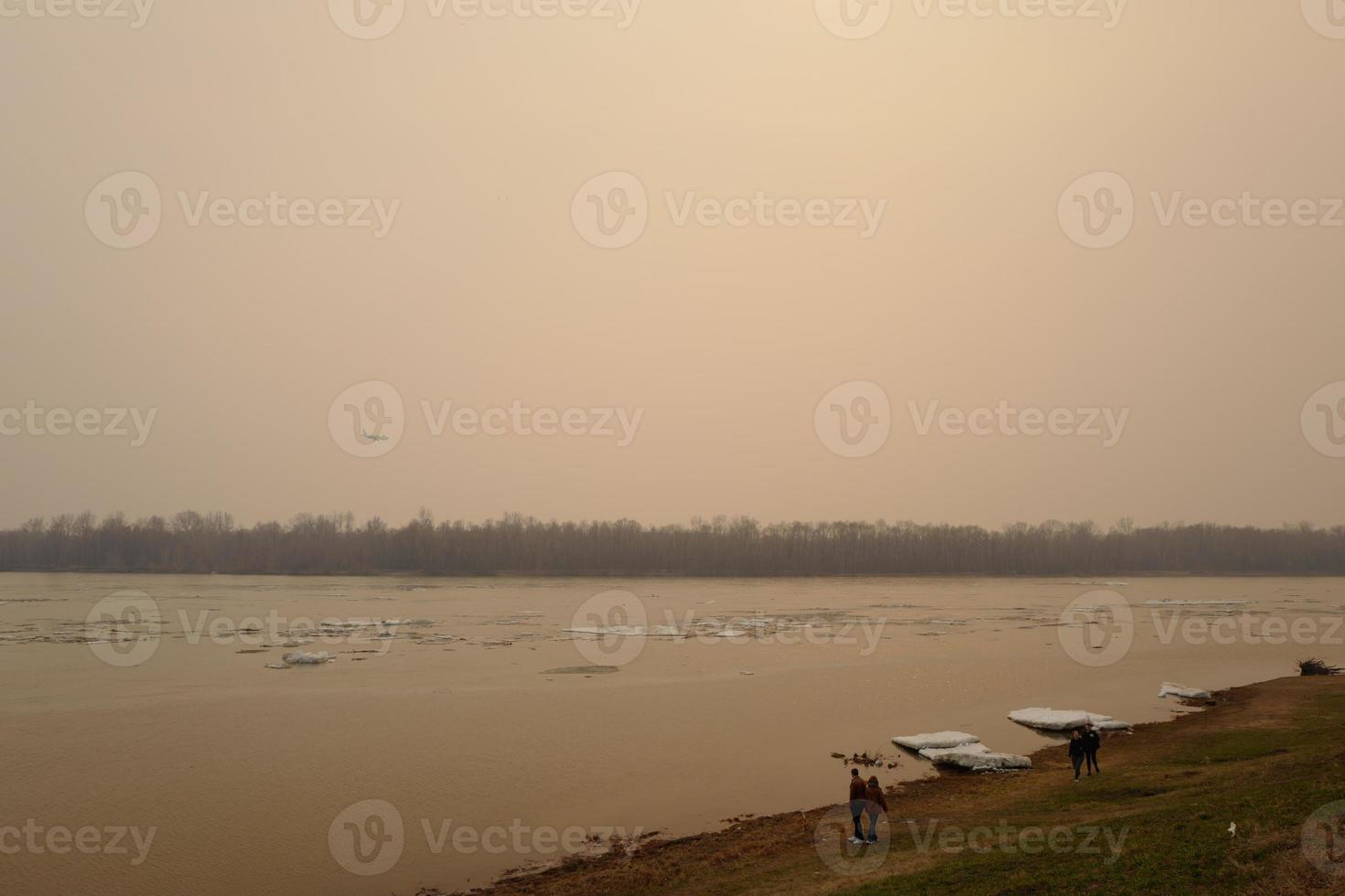 Ice on the Irtysh River. Slightly foggy evening. Airplane in the sky. Omsk, April 17, 2022. photo