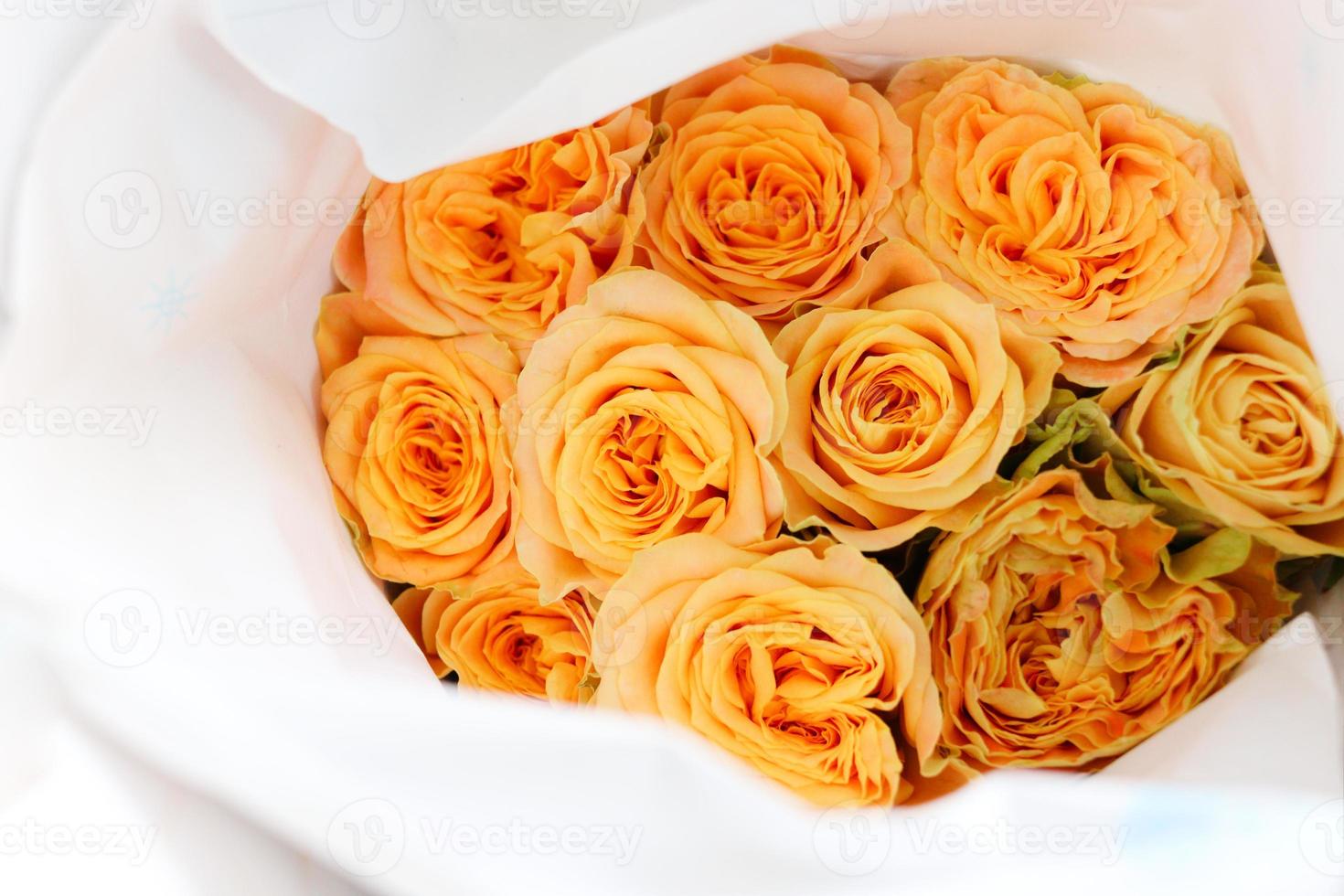 hermosa rosa naranja envuelta en papel a la venta en el mercado de las flores, regalo presente en el día de san valentín. foto