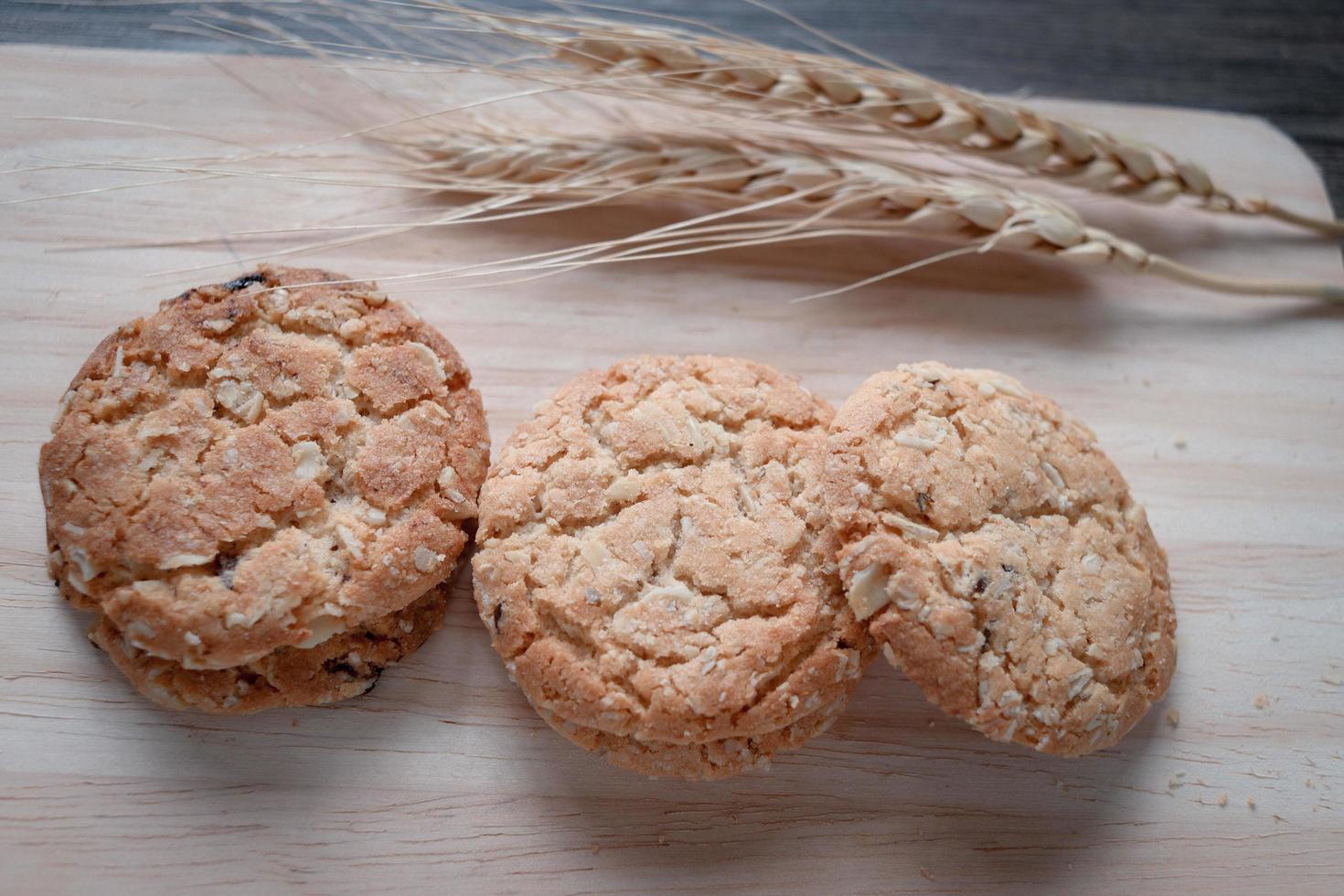 tres deliciosas galletas de avena con espiguillas en tabla de cortar de madera en la mesa. foto