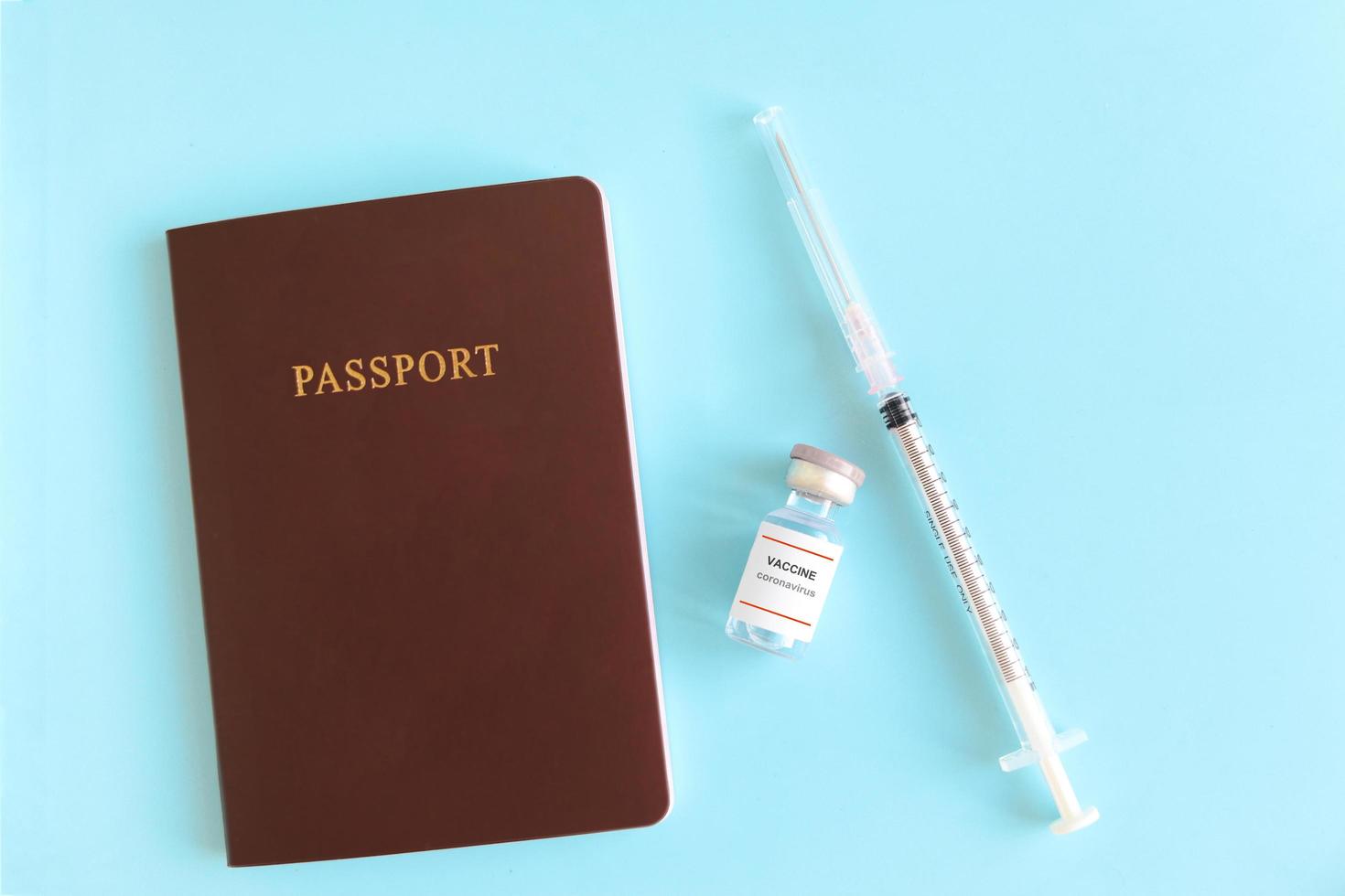 pasaporte con vial de vacuna y jeringa de aguja sobre fondo azul, viaje de seguridad en viaje de vacaciones de viajero que ha sido vacunado con la vacuna coronavirus covid-19. foto