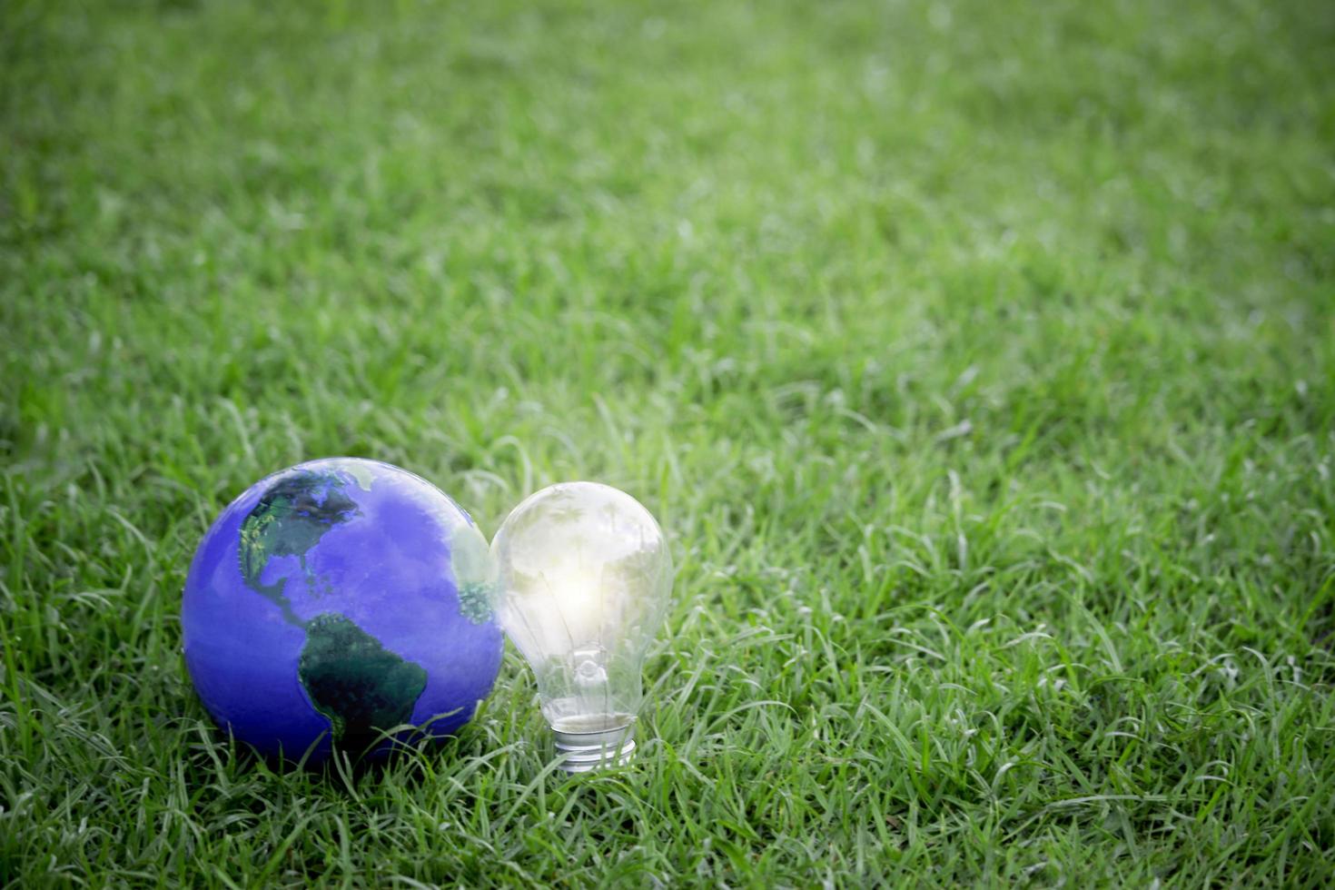 Earth with light bulb on green grass, energy-saving, save the world, love and protect our planet, environmental  friendly concept photo