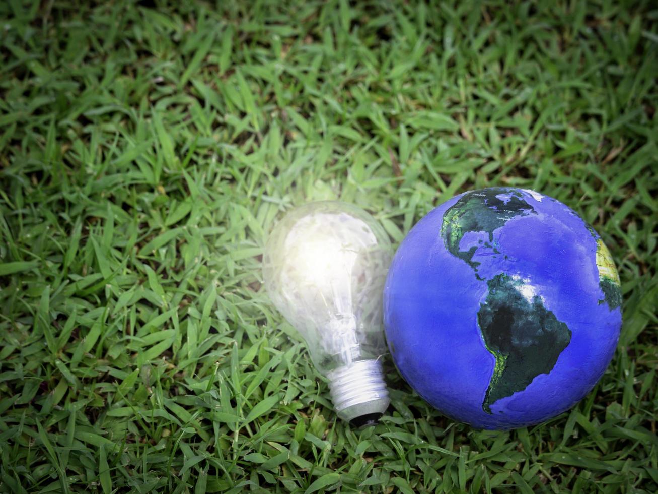 Earth with light bulb on green grass, energy-saving, save the world, love and  protect our planet, environmental  friendly concept photo