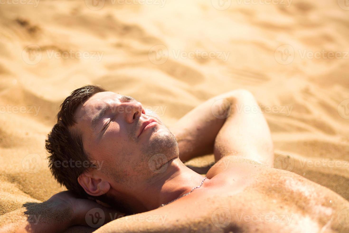 A man is sunbathing on the hot yellow sand. Beach holidays, a resort on the seashore. Sun protection, UV rays, sunscreen filter, SPF. Skin health photo