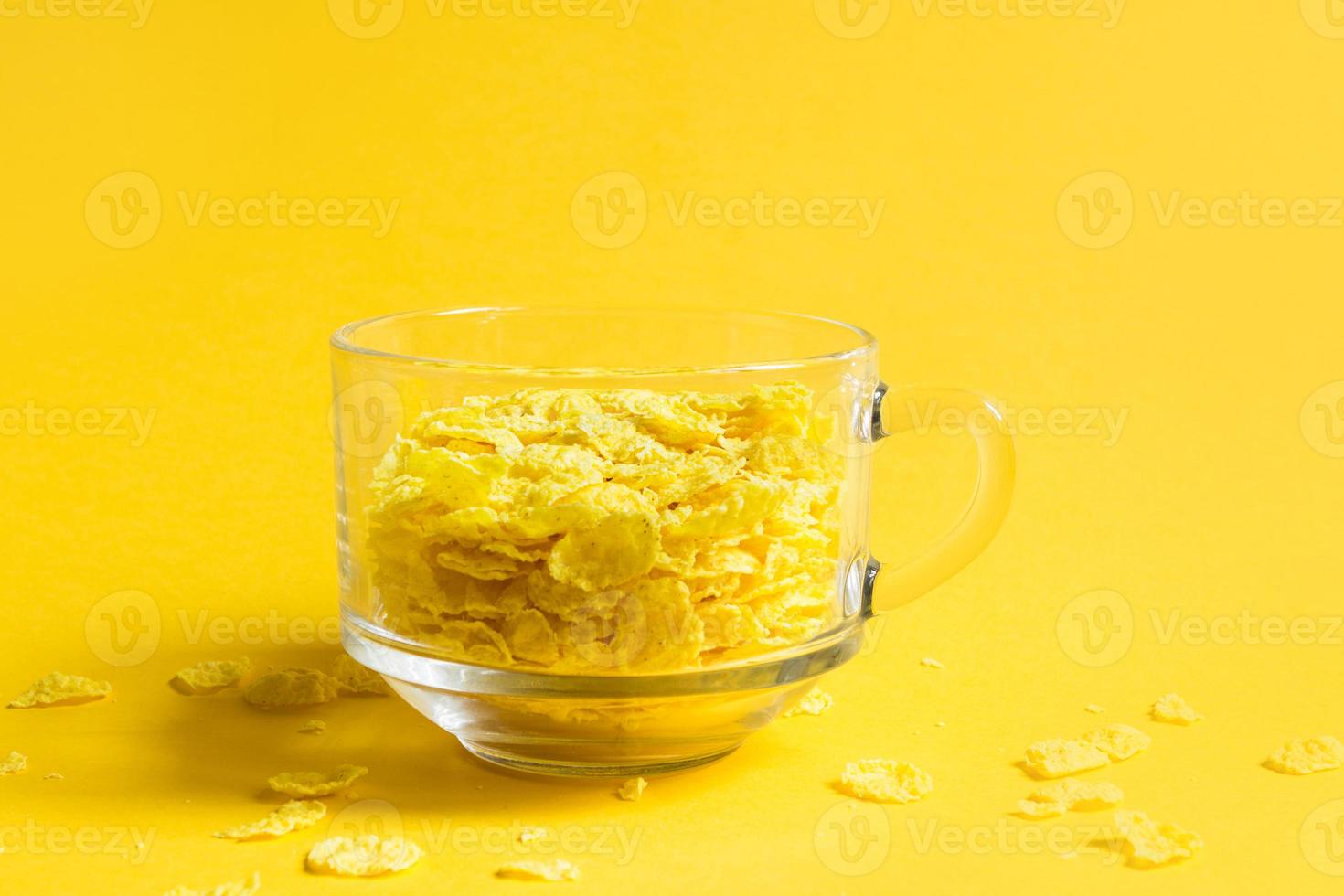 Transparent bowl with corn and multigrain flakes on a yellow background. Quick and healthy breakfast photo