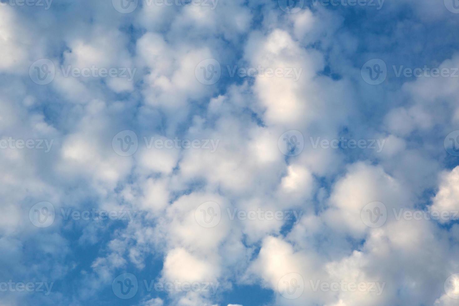 White cumulus clouds in a blue sky. Backgrounds with a pattern of high-beam clouds. Weather, seasonality, ecology, clear sky. photo