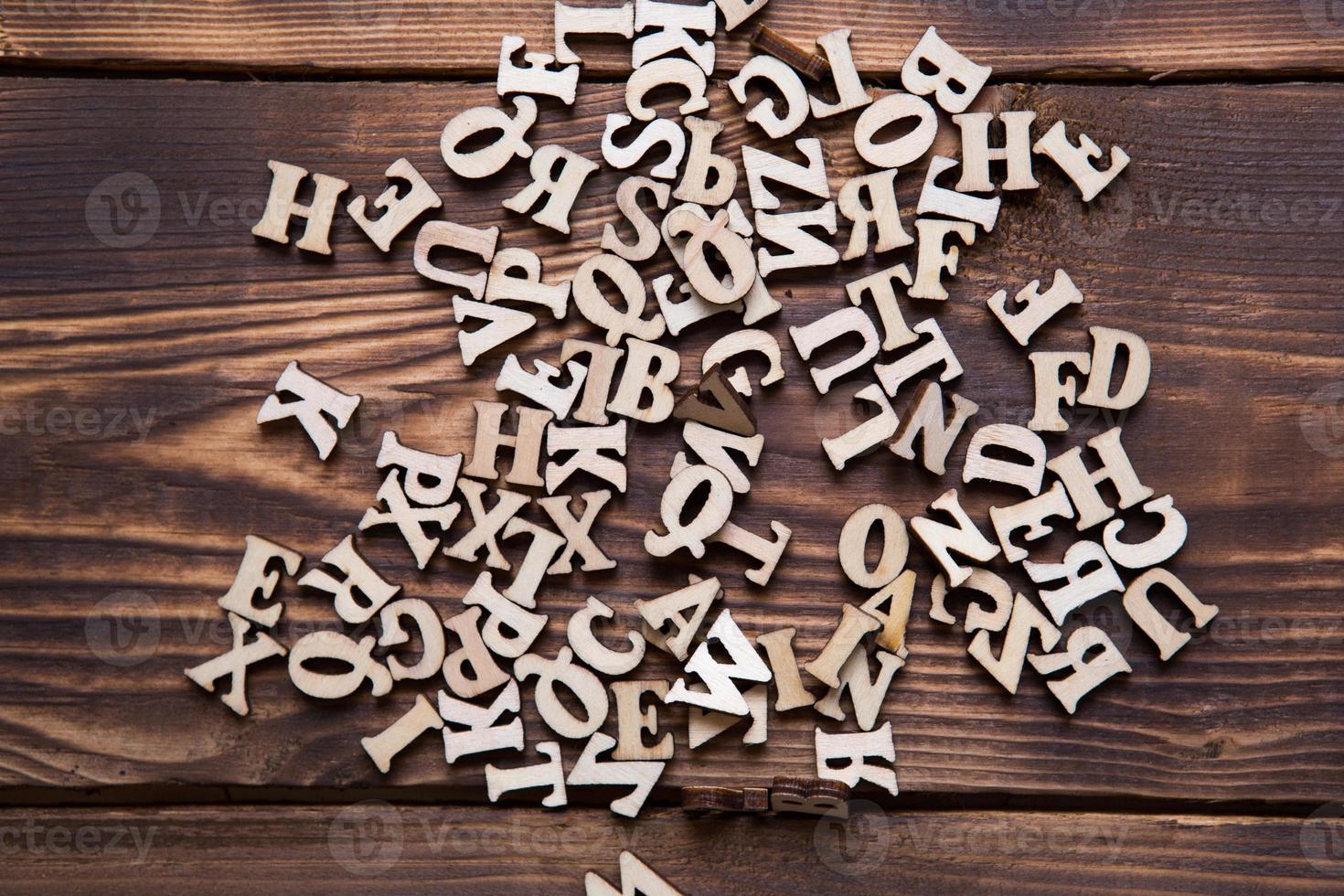 Letters of the English alphabet on a dark wooden background. The concept of education, word games, needlework. Space for text photo