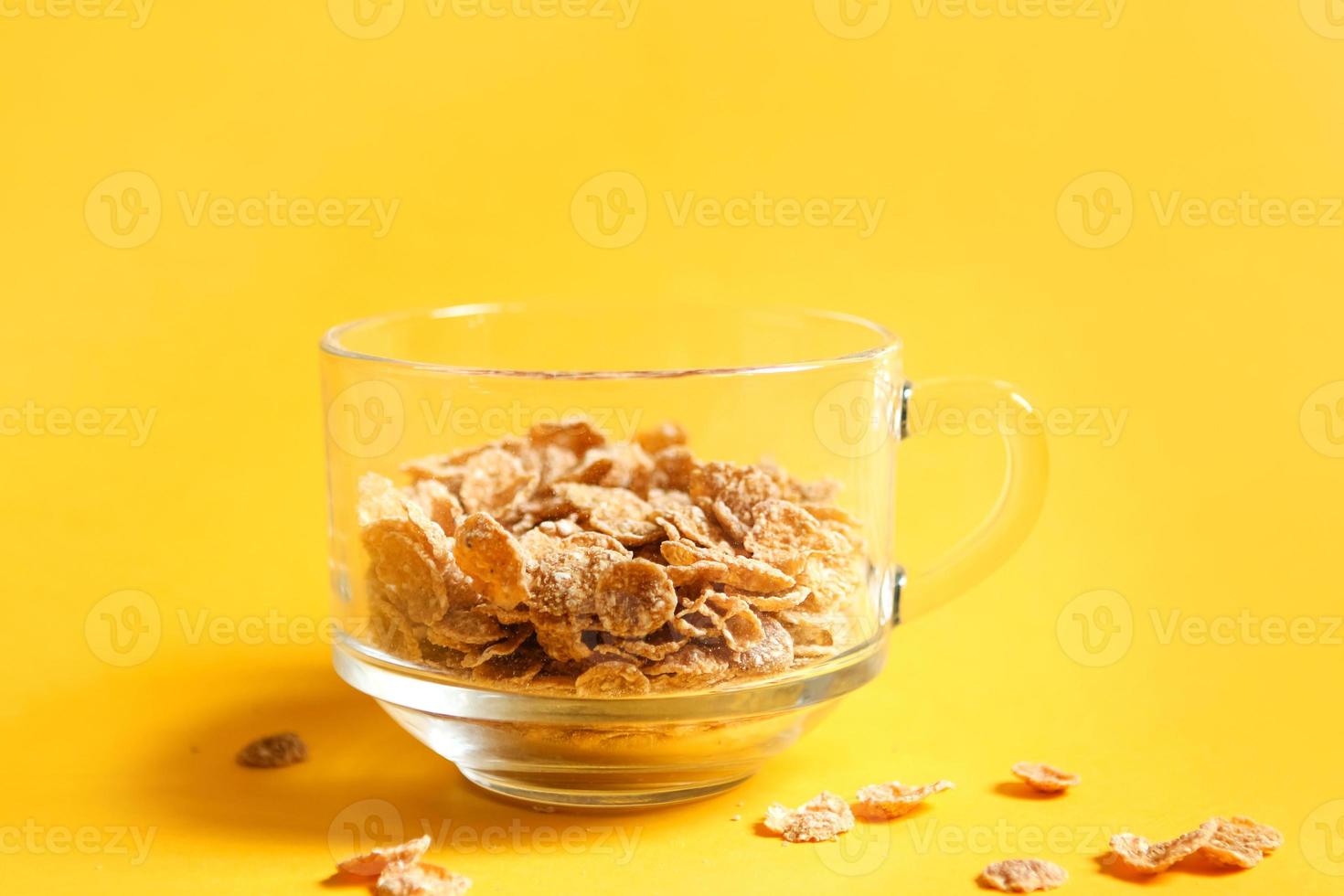 Transparent bowl with corn and multigrain flakes on a yellow background. Quick and healthy breakfast photo
