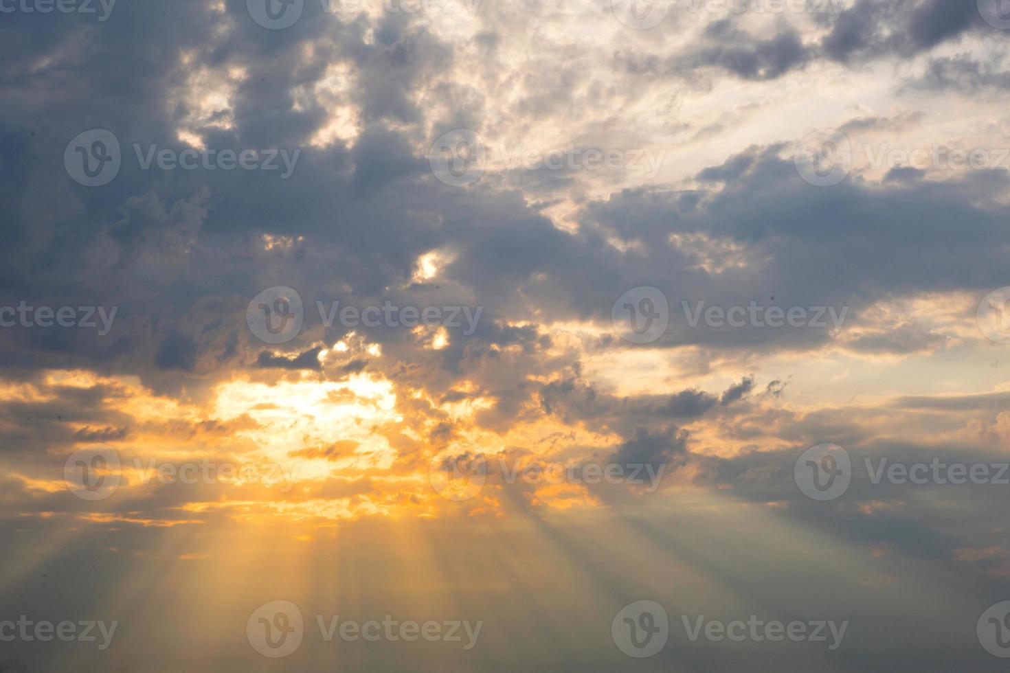 Orange rays of the sun through cumulus clouds in the sky at sunset in summer. Heavenly magic light. photo