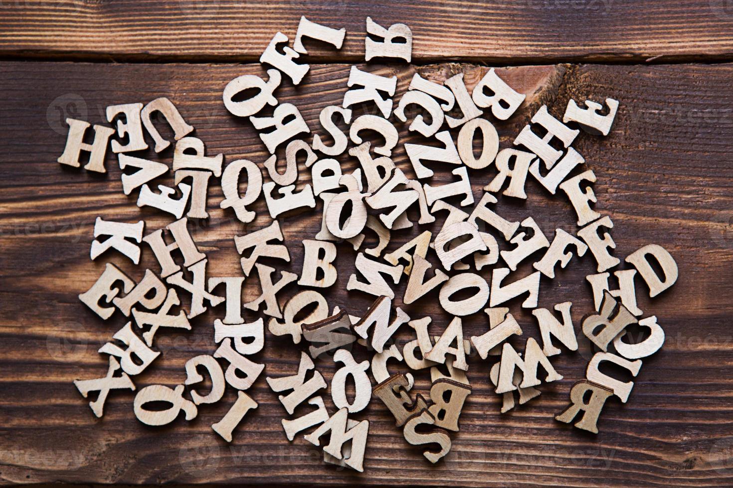 Letters of the English alphabet on a dark wooden background. The concept of education, word games, needlework. Space for text photo