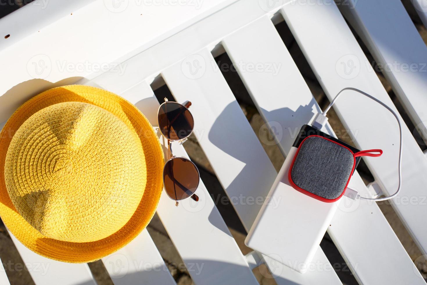Music portable speaker is charged from the power bank via usb on a deck chair near the pool with beach accessories. Always in touch, travel gadgets, external battery for a smartphone. Place for text. photo