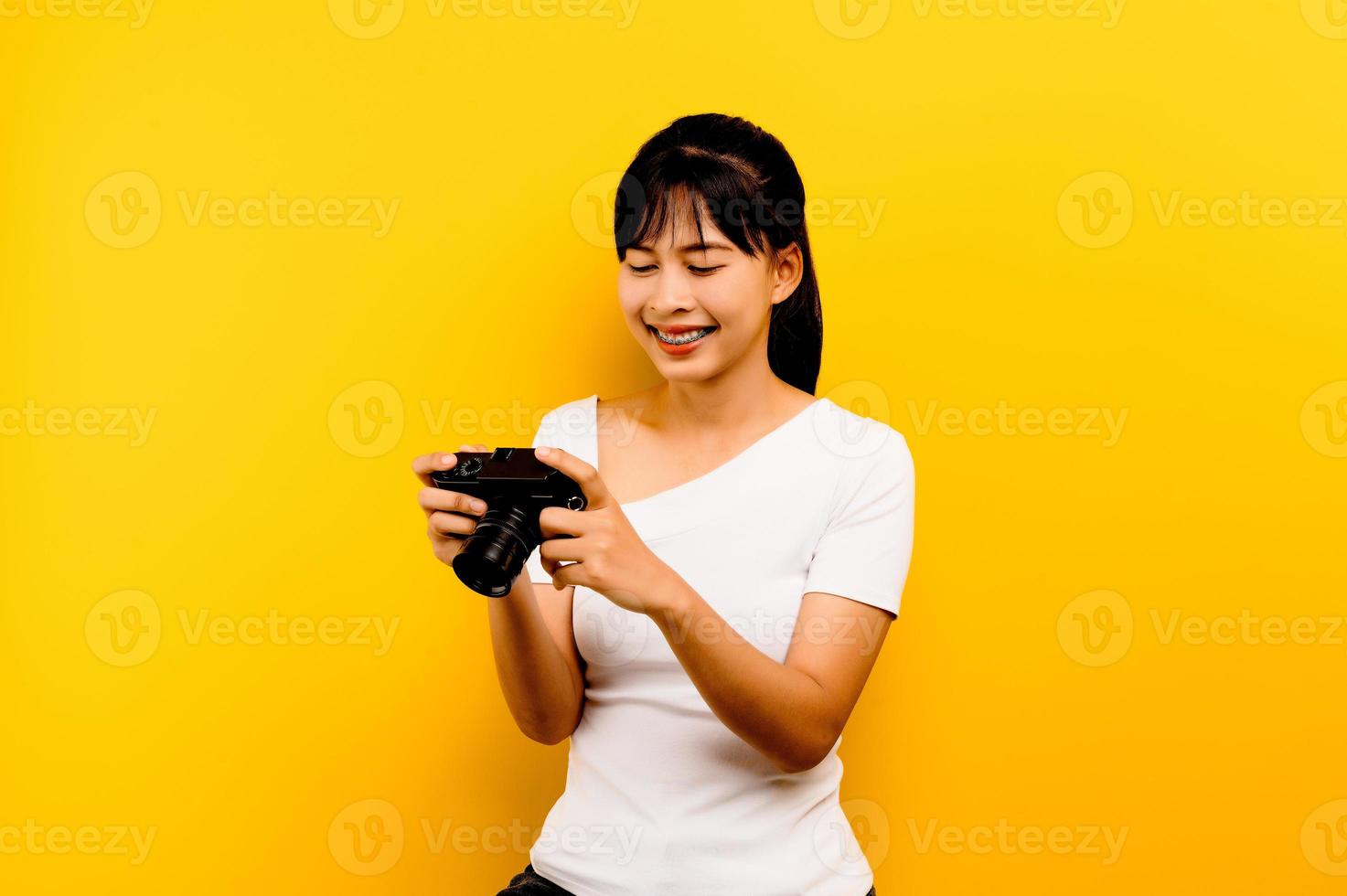 chica fotógrafa tomando fotos. modelo aislado sobre fondo amarillo. con espacio de copia foto