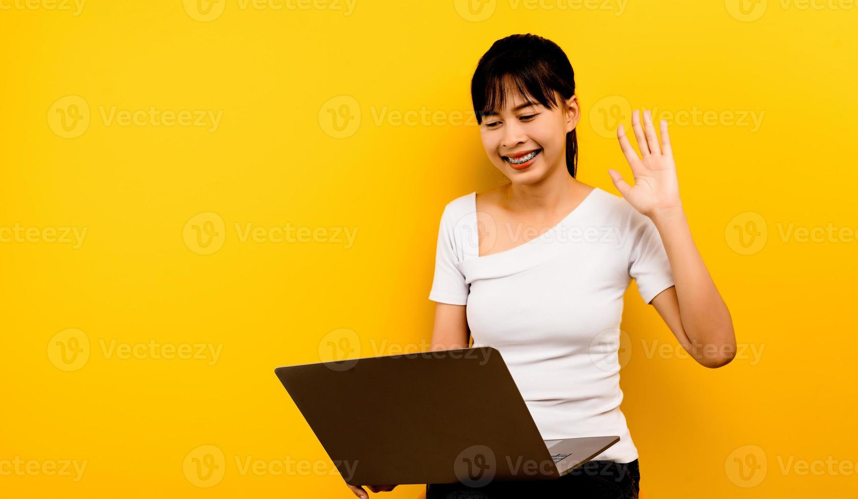 mujer y laptop discutiendo el trabajo en línea, foto de una atractiva mujer de negocios sonriendo felizmente navegando por Internet, tipo de laptop, correo electrónico aislado de fondo amarillo.