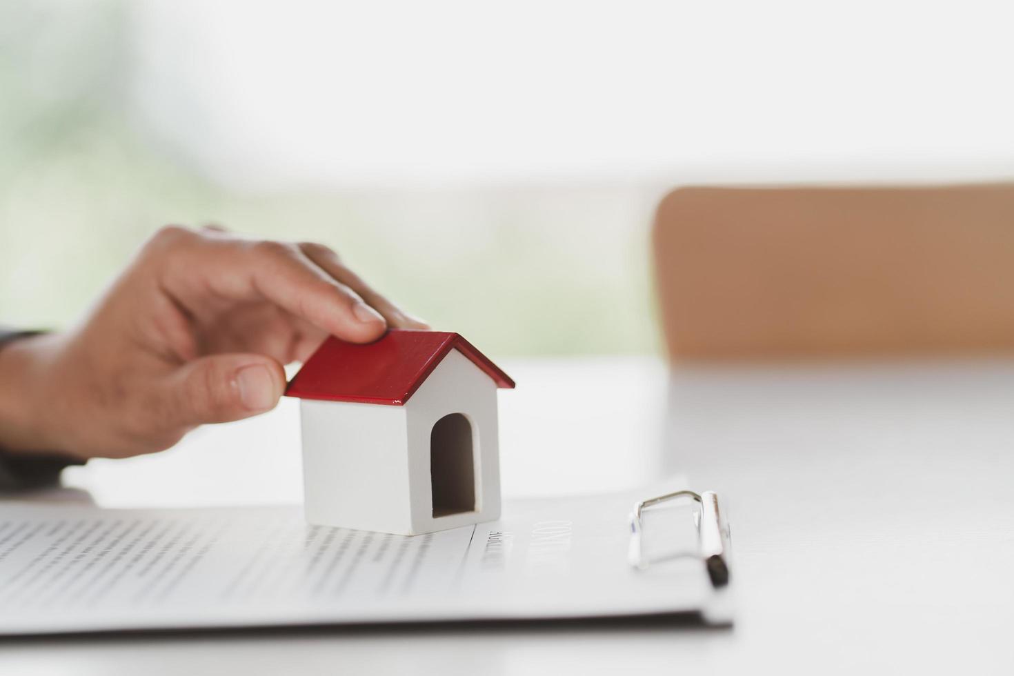 cerrar la casa de juguete de madera con el hombre firma un contrato de compra o una hipoteca para una casa, concepto de bienes raíces. foto