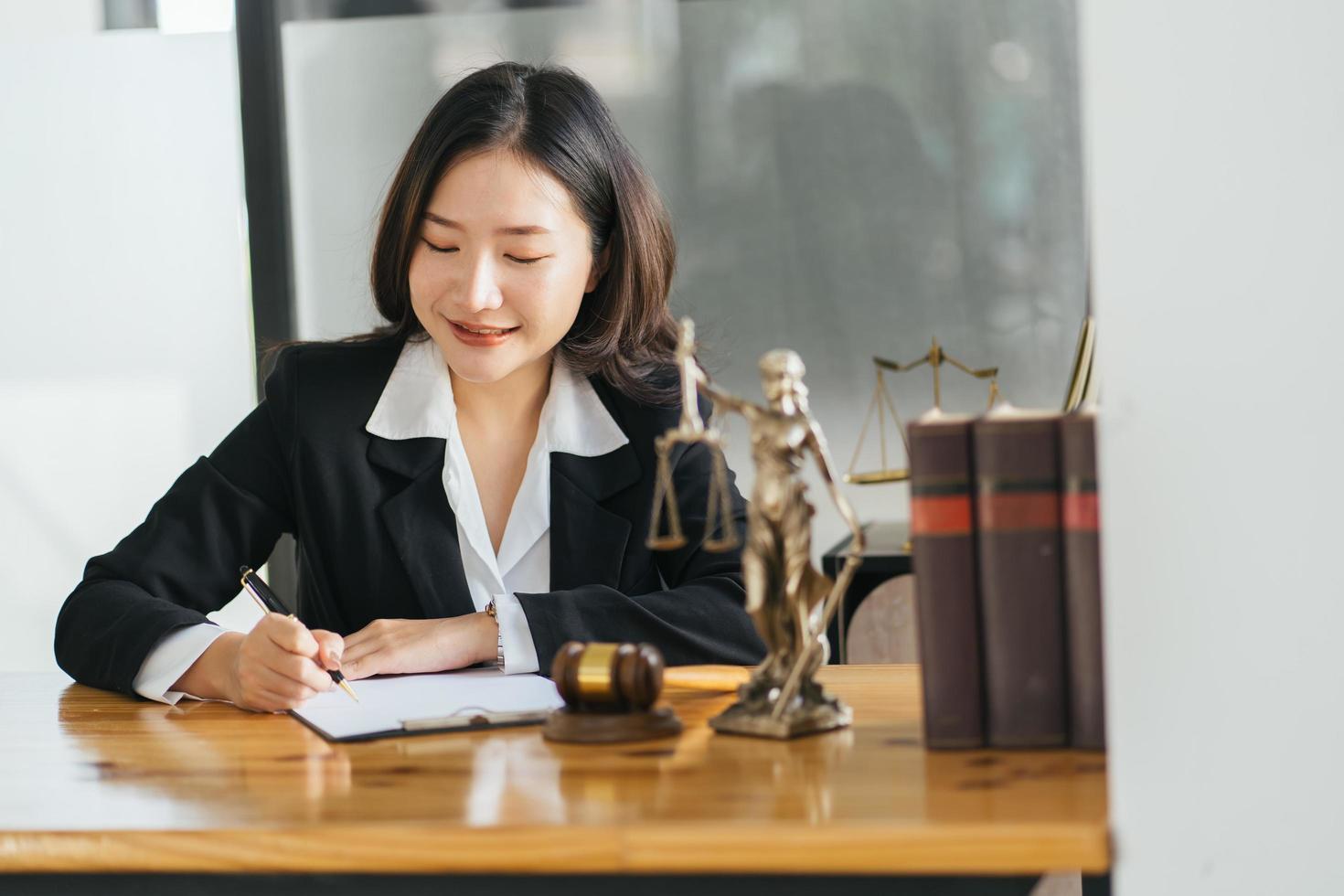 joven y seria mujer de negocios asiática, abogada directora ejecutiva, sentada en un escritorio trabajando escribiendo en una computadora portátil en una oficina corporativa contemporánea. concepto de tecnologías empresariales. foto